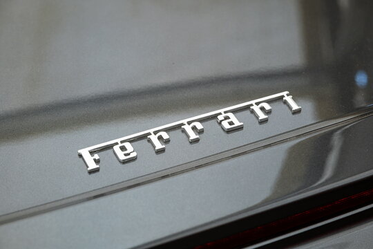 Lucerne, Switzerland, May 30, 2026. Polished chrome Ferrari script logo badge emblem on a metallic grey trunk lid