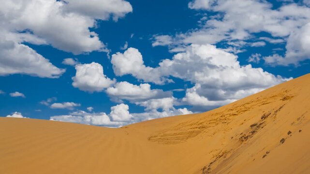 wide sandy dune in desert under a blue sky time lapse scene
