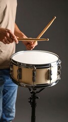Obraz premium Close-up of a person playing a snare drum with drumsticks on a gray backdrop