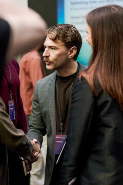 Male business professional greeting associates at meet and greet session in convention center