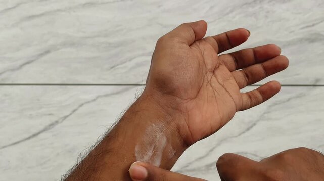 Finger applying or rubbing new cosmetic skincare product white cream wrist skin for testing irritation and allergy reaction before using on sensitive area like face. Extreme closeup top view.