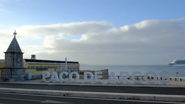 04 June 2026, Portugal, Paco de Arcos - Cruise ship arrives at Paco de Arguero in morning light, busy scenes by the shore. ship docks at harbor. cars pass by water. sky bright.  lively spot in morning