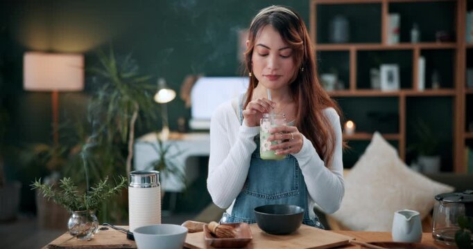 Matcha, drink and glass with woman in home for green tea, wellness and organic beverage. Antioxidant shake, traditional preparation and detox with person in living room of apartment for culture