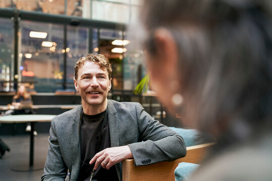 Smiling mature businessman communicating with expert at networking event in convention center