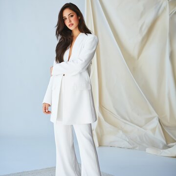 Model Poses in White Outfit Against Neutral Backdrop During Studio Shoot