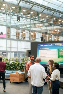 Male entrepreneur exchanging insights regarding AI's potential to mitigate energy crisis with attendees during conferenc