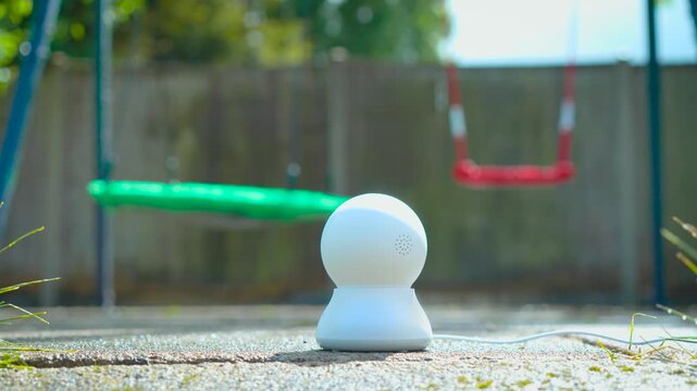 AI backyard camera monitoring children playground for family safety. Smart outdoor surveillance device supporting remote child supervision near garden swings. Connected home security technology for