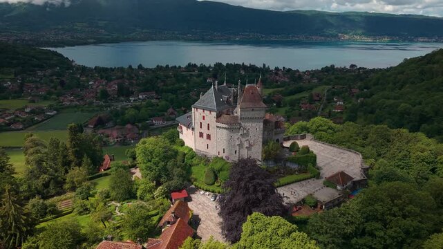 Aerial shot around Menthon Saint Bernard castle with the Lac d'Annecy in the background on a sunny day of spring in Haute SAvoie departement, Auvergne Rhone Alpes region, France