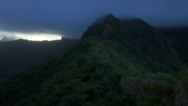 Tahiti Moorea island French Polynesia Belvedere Lookout Mount Toheia Mt Rotui aerial drone sunset low dark cloud layer lush green jungle forest volcanic jagged rugged mountain peaks forward pan up