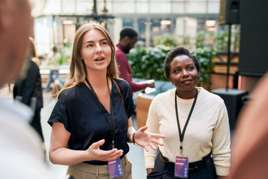 Female business expert exchanging ideas with executives regarding connectioneering during event at convention center