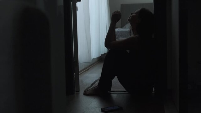 Broken hearted woman sitting alone in dark room after breakup