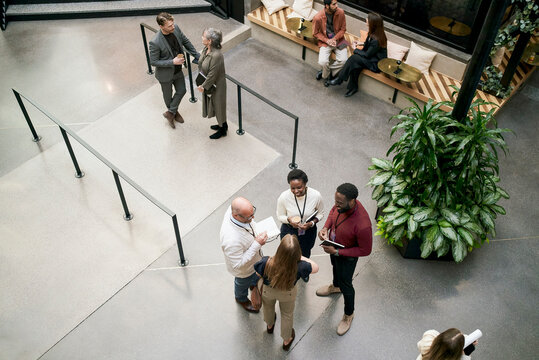 High angle view of smiling male and female business executives interacting with each other with standing in convention c