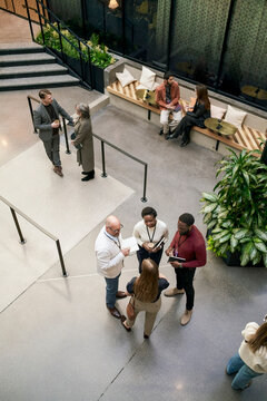 High angle view of smiling male and female business associates interacting with each other with standing in convention c