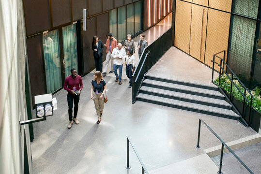 High angle view of female and male business associates talking with each other while walking in lobby of convention cent