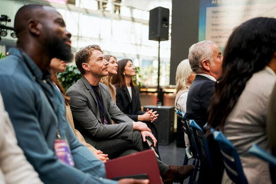 Businessman attending seminar with executives while sitting in convention hall
