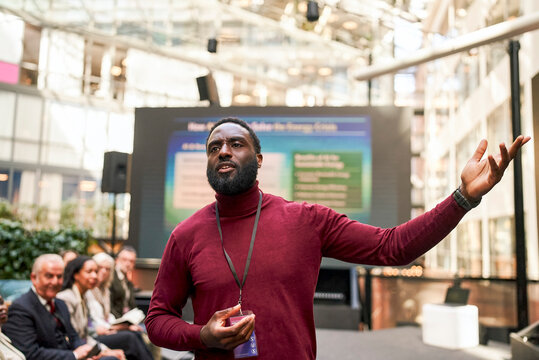 Male speaker explaining points while presenting slide show in business conference at convention center