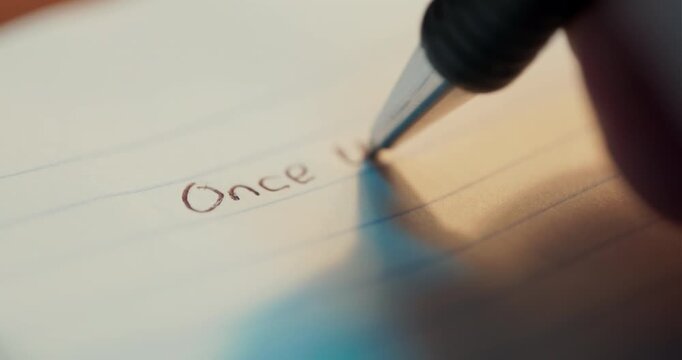 A macro shot of a black pen writing the words Once Upon a Time on lined paper, suitable for storytelling, literature, and creative education concepts.