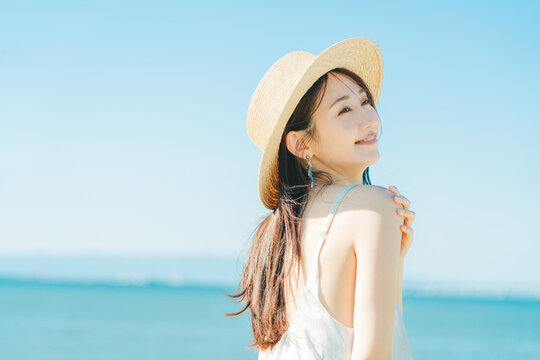 海と青空バックの麦わら帽子を被った女性