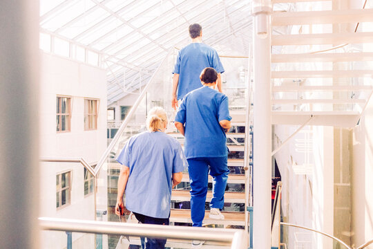 Rear view of male and female medical professionals moving up on steps in hospital building