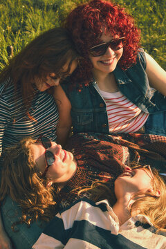 Close up of young women resting together on grass with retro effect. Concept of intimate friendship, warm emotions, nostalgic summer portrait, and relaxed outdoor lifestyle.