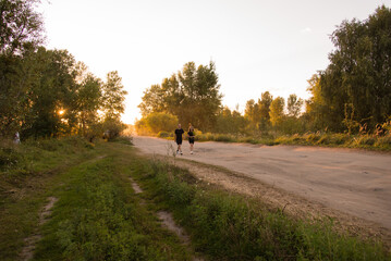 Fototapeta premium Beautiful couple in love walking in a field on a meadow at sunset. Teenagers holding hands