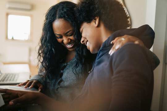 Happy woman embracing son doing studies at home