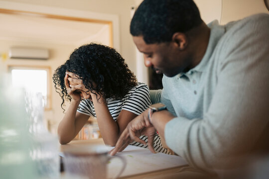 Father helping frustrated daughter during home study session