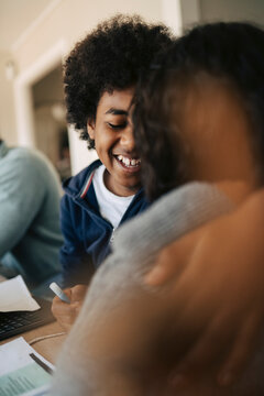 Happy boy laughing with mother while studying at home