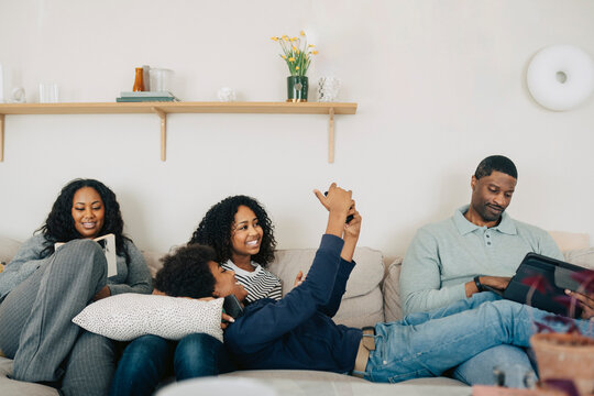 Happy family spending quality time together while using different electronic devices at home