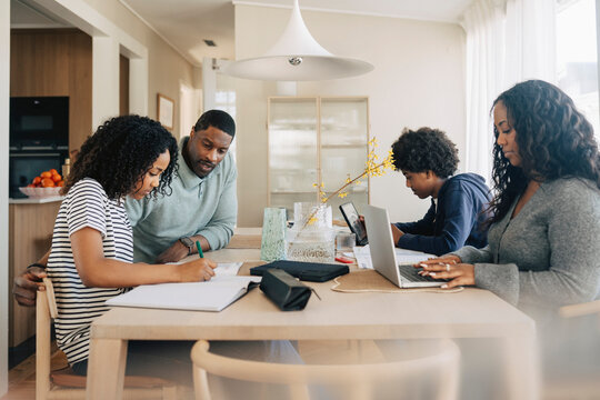 Busy family sitting together at dining table while working and studying from home
