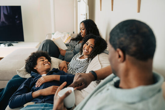 Happy children spending leisure time with father while sitting on couch at home