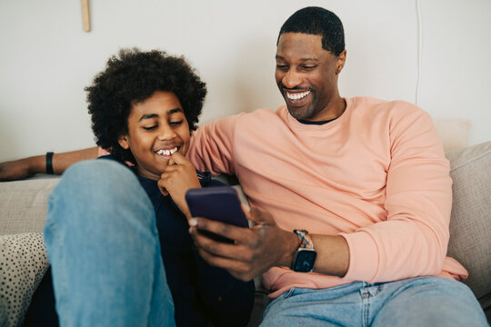 Happy father and son spending quality time with each other using smart phone at home