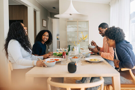 Happy family enjoying lunch while sitting around dining table at home