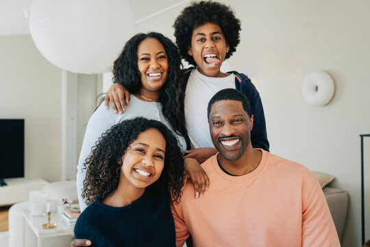 Portrait of smiling man and woman posing with their children in living room at home