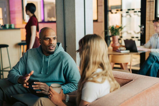Diverse colleagues having serious discussion while sitting on couch in office lounge