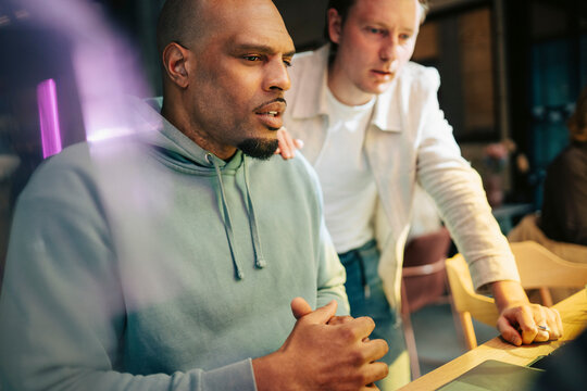 Focused male entrepreneurs reviewing data and discussing while working at office
