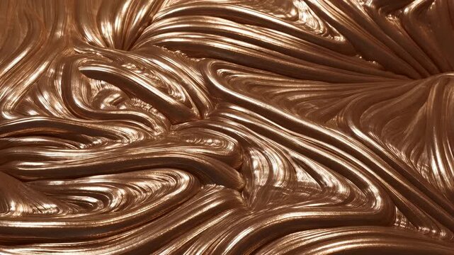 Slow motion close up tracking shot of metallic bronze liquid swirling and folding across glossy surface on tabletop studio set