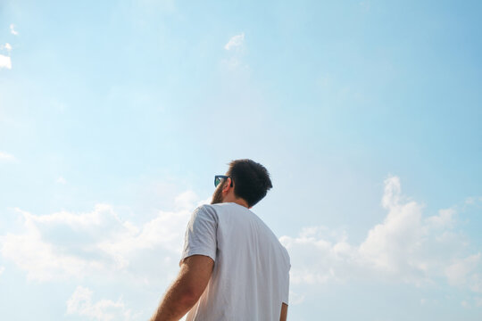 Man looking up at the blue sky on a sunny day