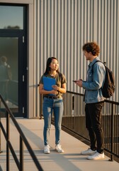 Obraz premium Diverse University Students Having a Conversation Outside Modern Campus Building at Sunset