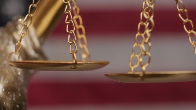 Golden scales of Justice Themis Statue swinging as symbol of weighing good and evil, guilt and innocence close-up