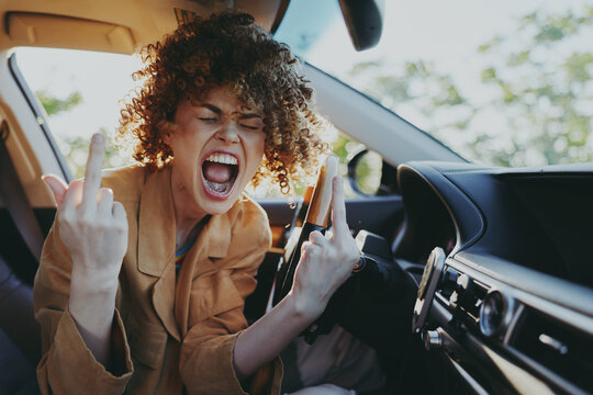 Energetic woman inside a car, shouting playfully, bold expression, sunlit interior, retro film color mood, candid lifestyle moment, vibrant and rebellious