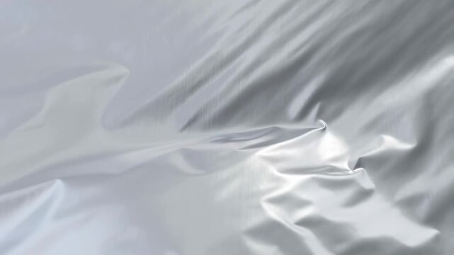 Slow motion close up of silver satin fabric creasing and unfolding on studio backdrop with reflective sheen and subtle texture