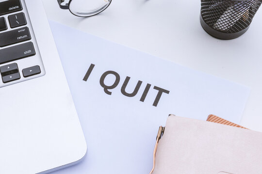 Flat lay conceptual composition of career change and workplace burnout featuring an explicit "I Quit" notice on a modern corporate desk
