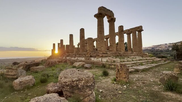 Ancient Greek temple ruins stand on a hill at sunrise in the Valley of the Temples, Agrigento, Sicily, Italy.