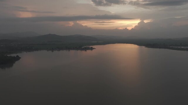 Sunset over Lak Lake in Lien Son Lak Commune, Dak Lak Province, Vietnam, featuring traditional wooden boats on the lake and peaceful rice fields surrounded by the Central Highlands landscape.