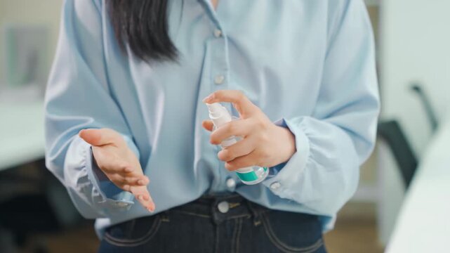 Unrecognizable businesswoman cleaning hands with sanitizer spray at workplace. Female disinfecting cleaning palms with alcohol from bacteria microbe spraying antibacterial because epidemic or pandemic