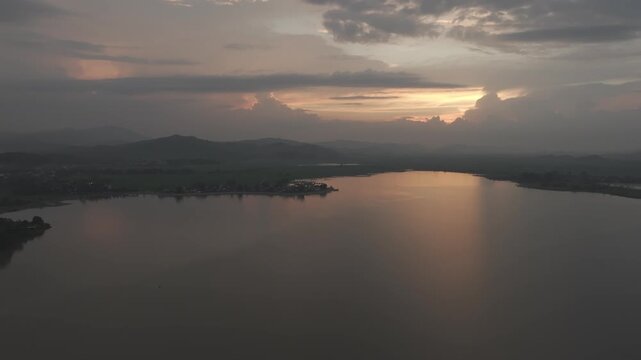 Sunset over Lak Lake in Lien Son Lak Commune, Dak Lak Province, Vietnam, featuring traditional wooden boats on the lake and peaceful rice fields surrounded by the Central Highlands landscape.
