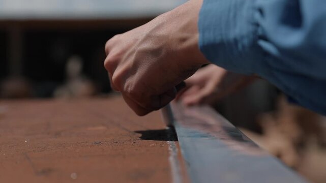 Craftsman's hands marking a traditional Ahlat stone with a straightedge and scribing tool.