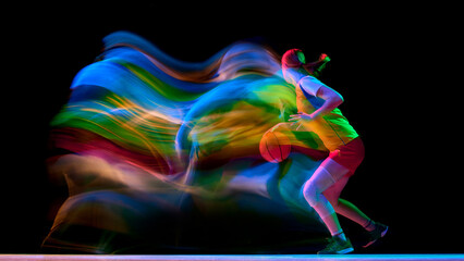 Female basketball player driving forward with colorful motion trail on black background. Concept of speed training, sportswear ads, energy posters, and performance campaigns.
