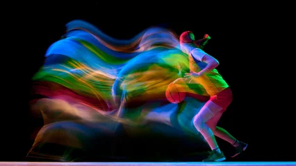 Female basketball player driving forward with colorful motion trail on black background. Concept of speed training, sportswear ads, energy posters, and performance campaigns. © master1305